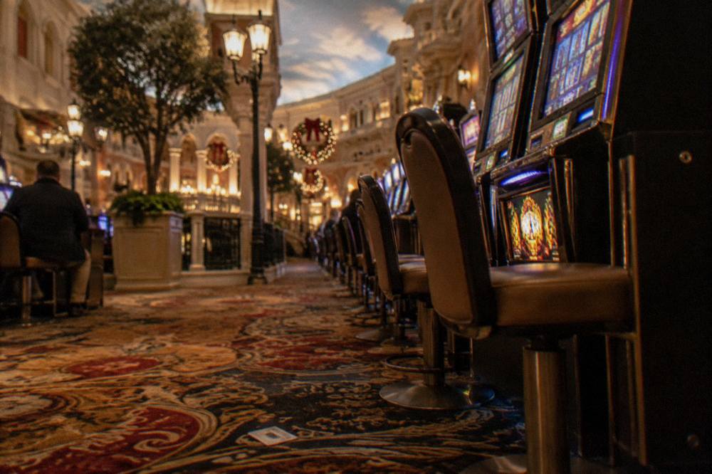 Long aisle of slot machines on a casino floor with warm evening lighting and holiday wreaths in the distance