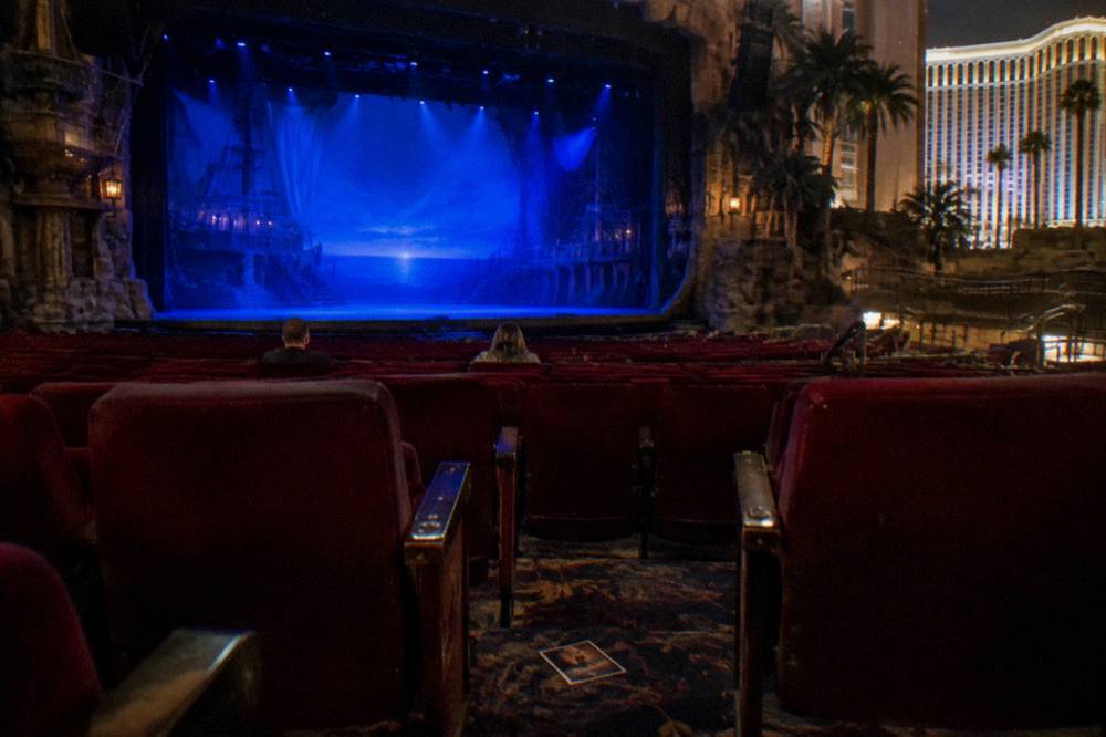Theater seating facing a stage lit in blue before an evening performance