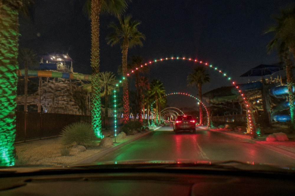 Strings of holiday lights glowing along a dark drive-through course at night