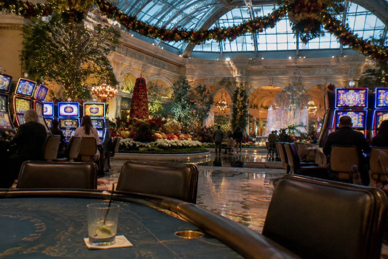 Wide casino gaming floor with banks of slot machines and strings of holiday garland overhead in evening light