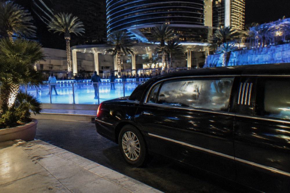 A black stretch limousine parked at the curb of a resort driveway at night