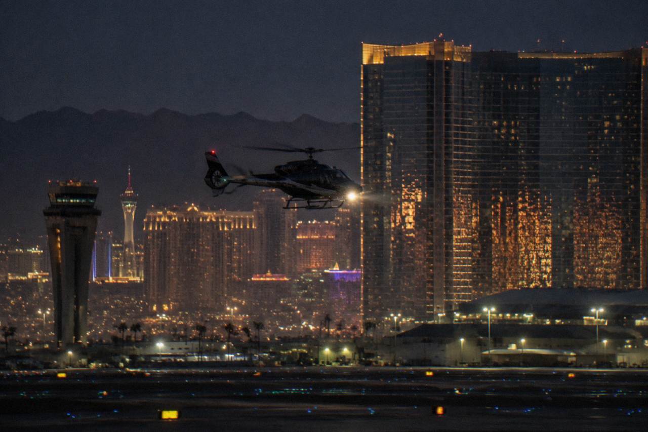 A helicopter flying over illuminated resort towers on the Las Vegas Strip at night
