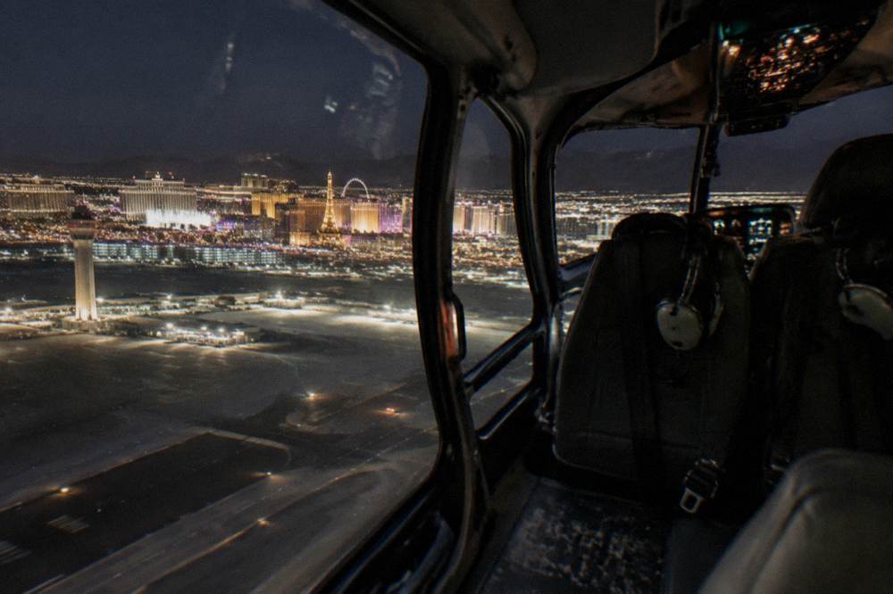 A helicopter cabin interior with city lights visible through the windows at night