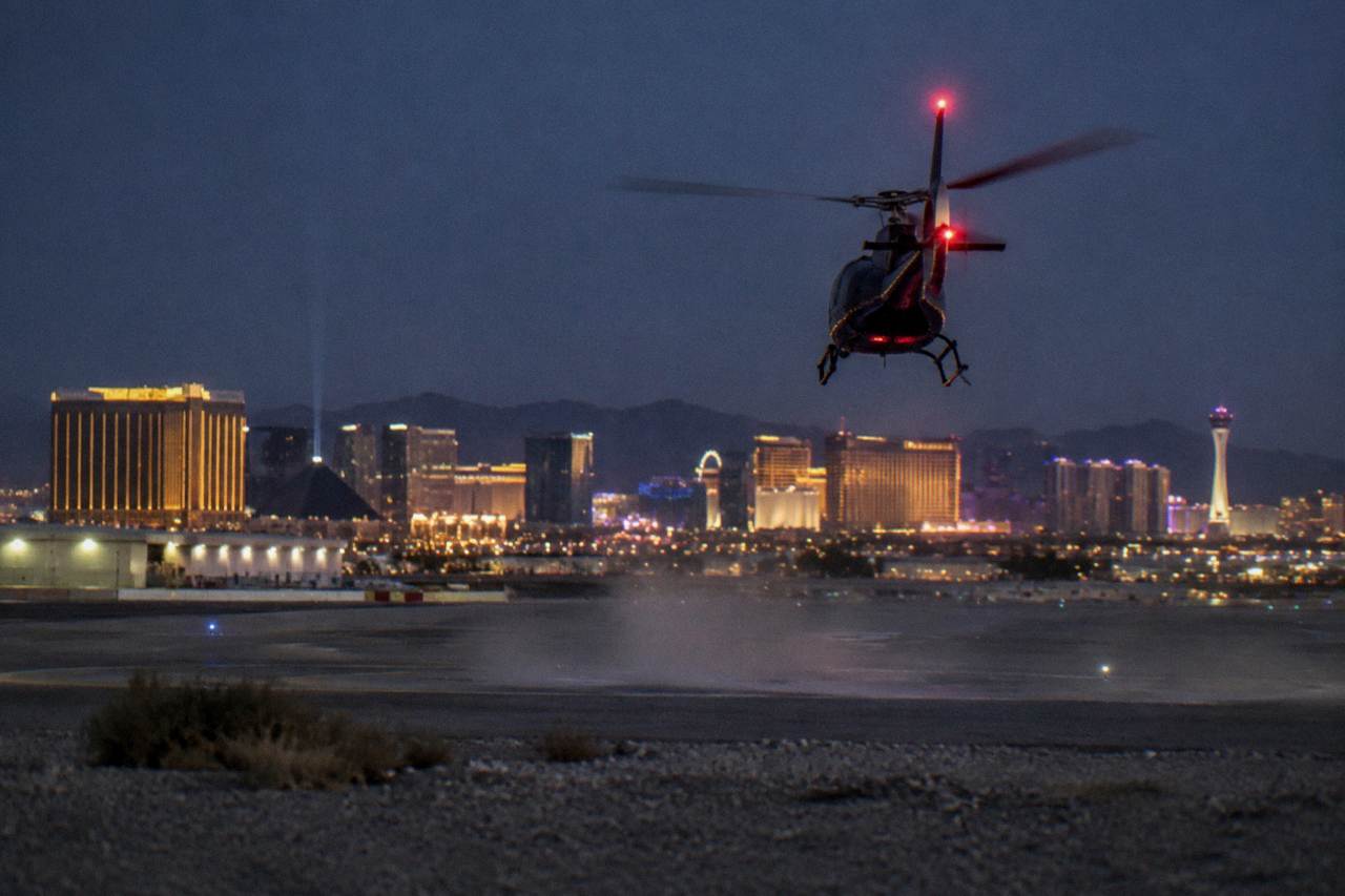 A helicopter flying over illuminated resort towers on the Las Vegas Strip at night