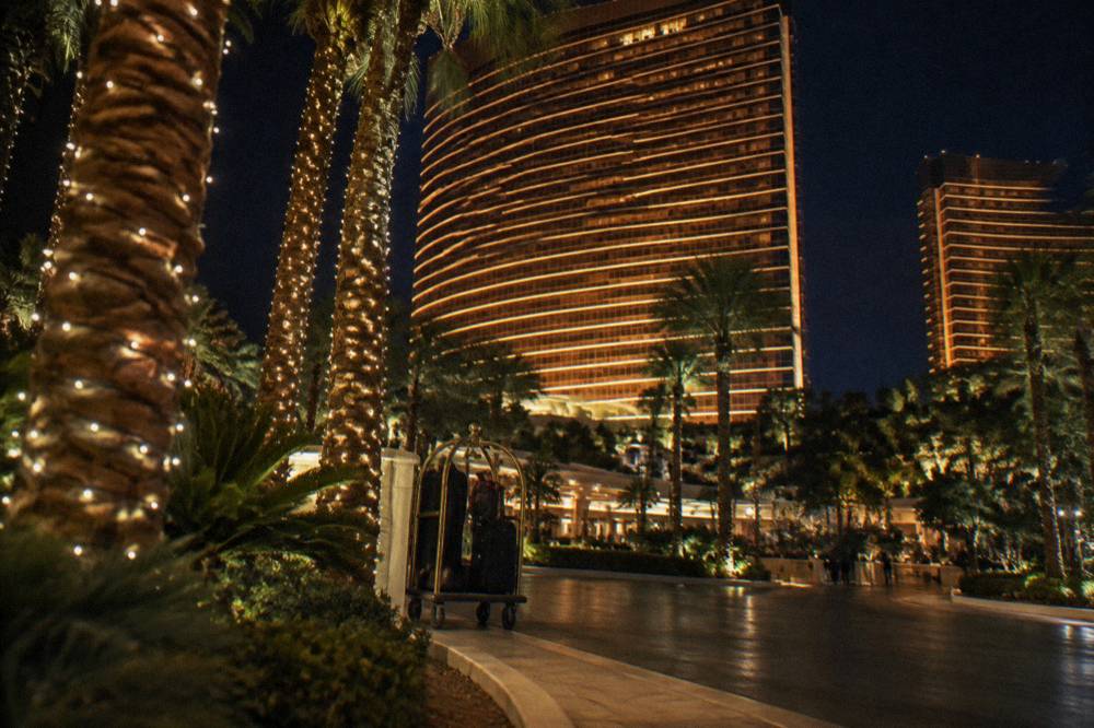 A Las Vegas resort tower and palm trees lit at night under a clear winter sky