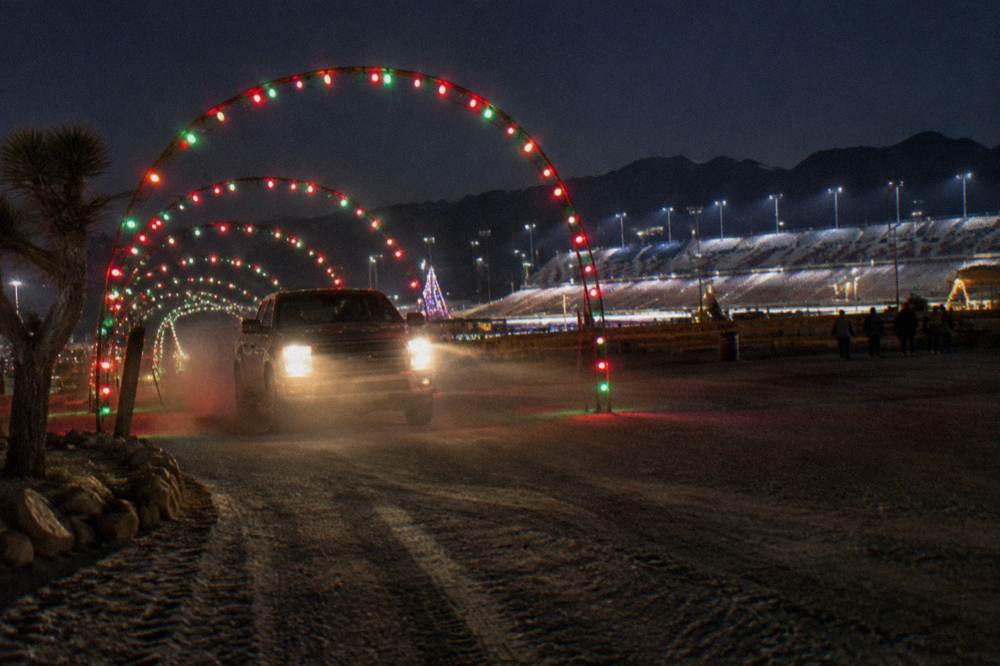 A tunnel of colorful holiday lights over a drive-through display course at night