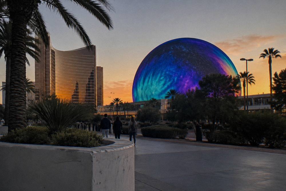A brightly lit spherical arena beside a resort tower on the Las Vegas Strip at dusk
