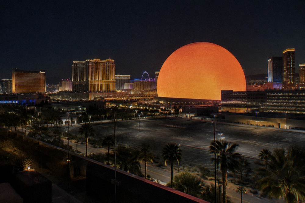 A glowing spherical venue and resort lights reflected across the Las Vegas skyline on a clear winter night