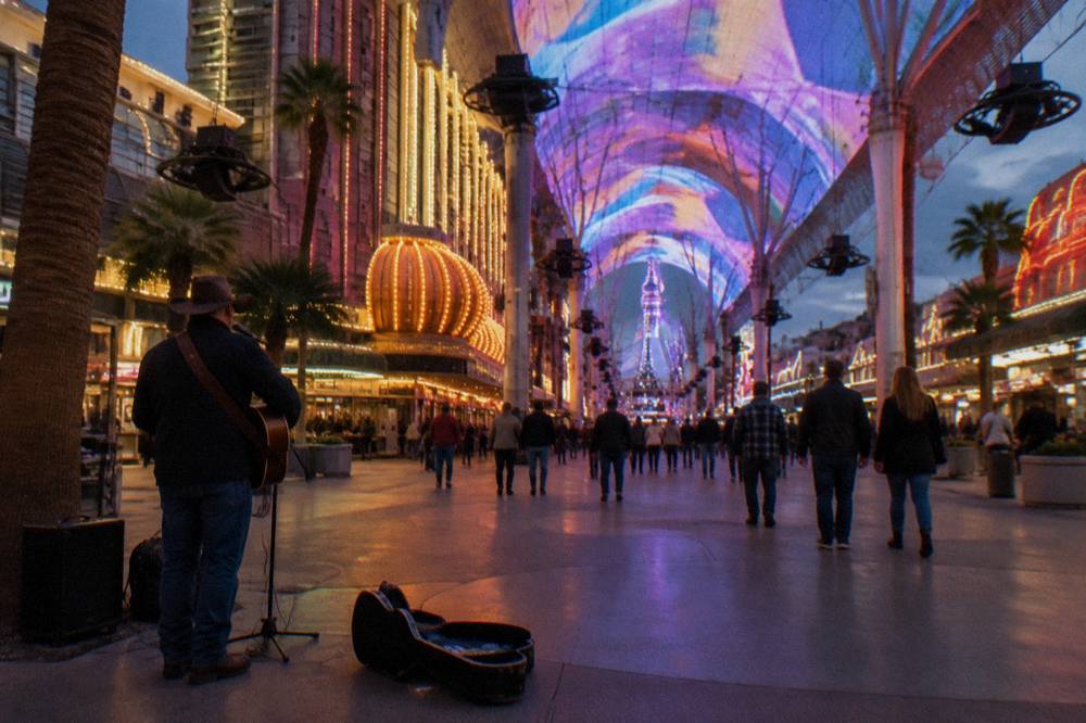 A long illuminated canopy of lights spanning a pedestrian street lined with glowing casino signs