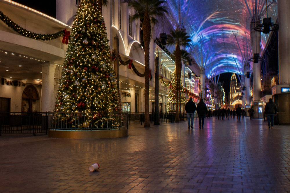 A downtown street at night with a large glowing Christmas tree and festive light decorations