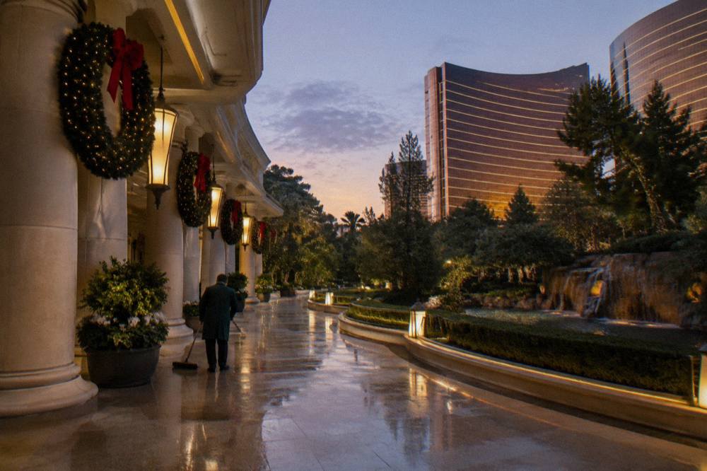 A quiet Las Vegas resort walkway lined with holiday wreaths and glowing lamps at twilight