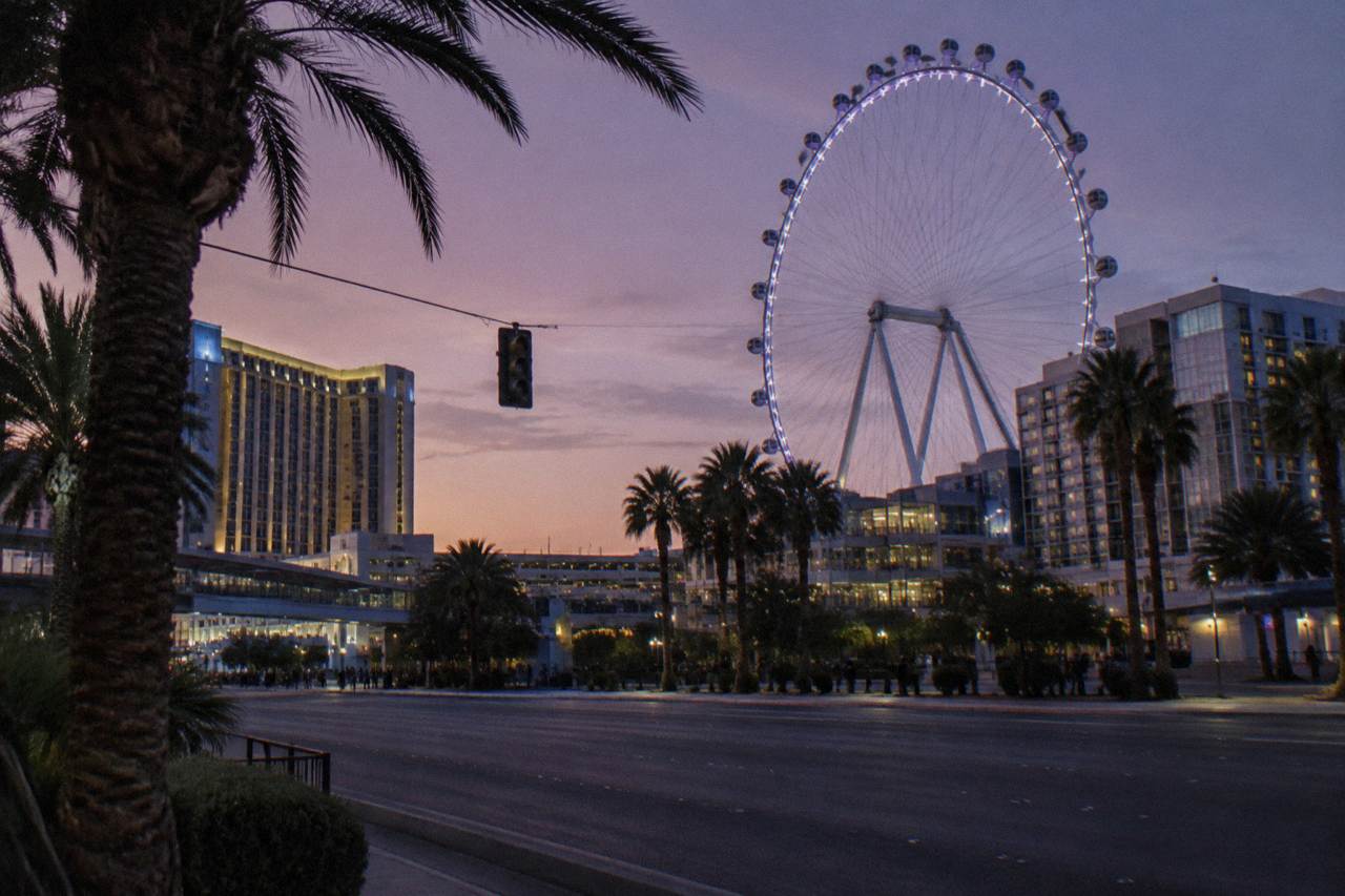 A Las Vegas resort boulevard at dusk with lit towers and light traffic on the road