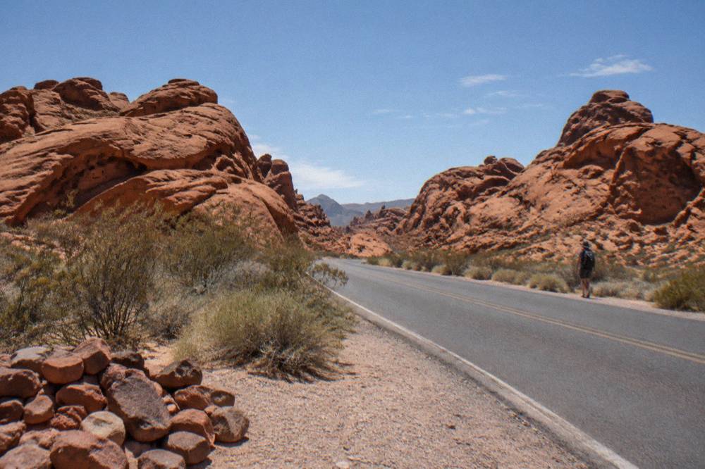 Red sandstone rock formations rising above a quiet desert road at midday