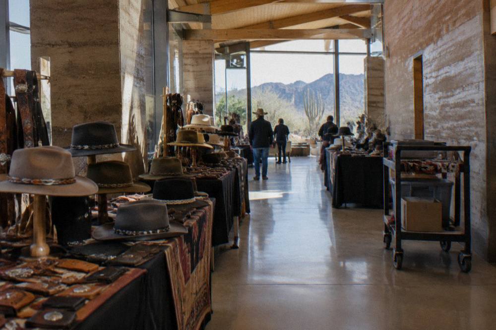 Rows of vendor booths with Western hats and leather goods inside a large exhibition hall