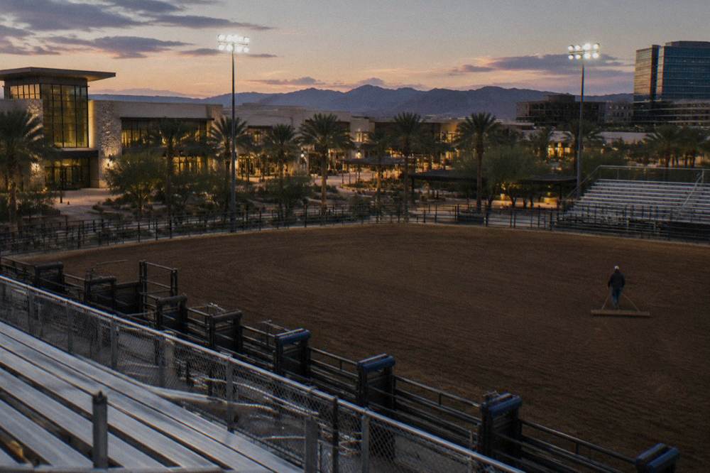 Rodeo bucking chutes and arena fencing under floodlights before a performance