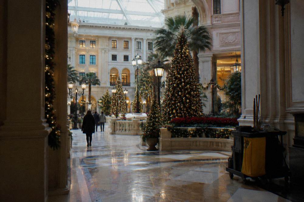 A grand hotel atrium filled with festive seasonal decorations and tall lit trees