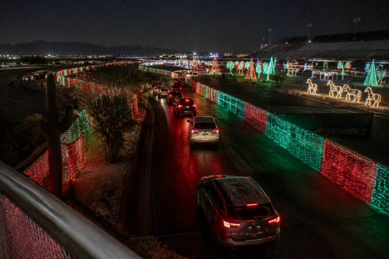 Holiday light displays glowing along a dark outdoor course at night
