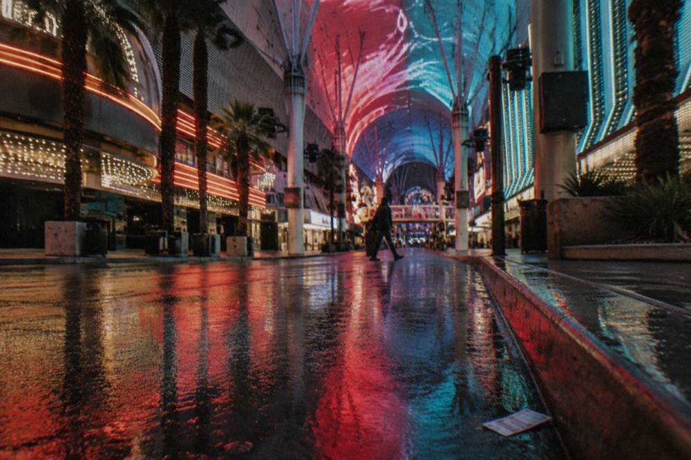 A quiet downtown Las Vegas street with neon signs reflecting on the pavement at night
