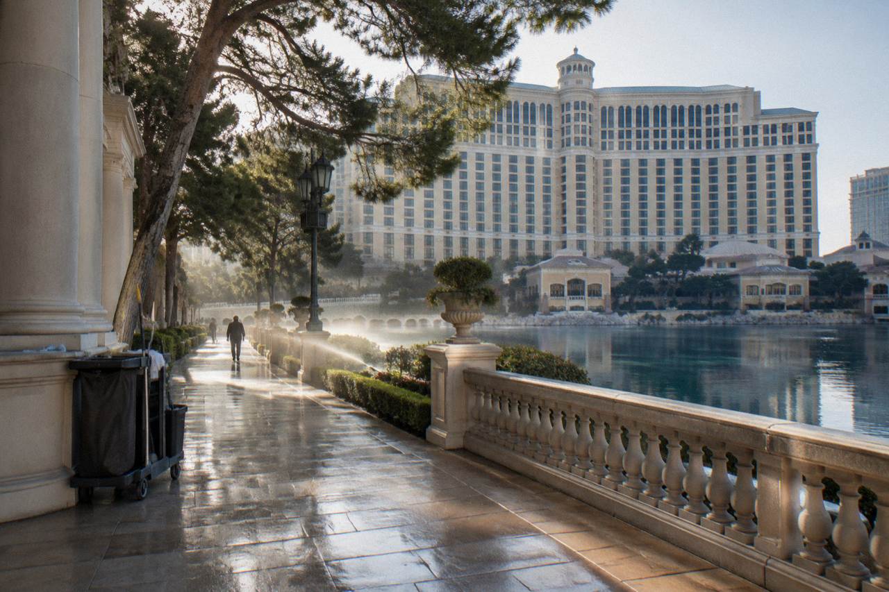 A quiet Las Vegas Strip sidewalk at dusk with resort towers glowing against an orange sky