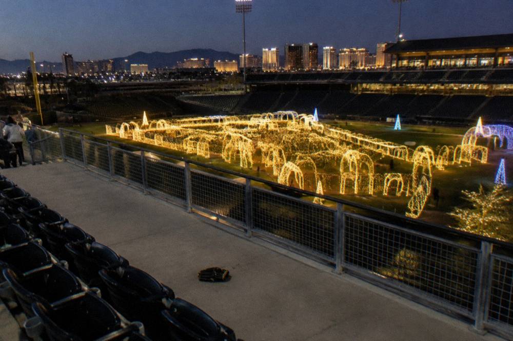 A walk-through holiday light maze with glowing arches and a lit path winding between trees