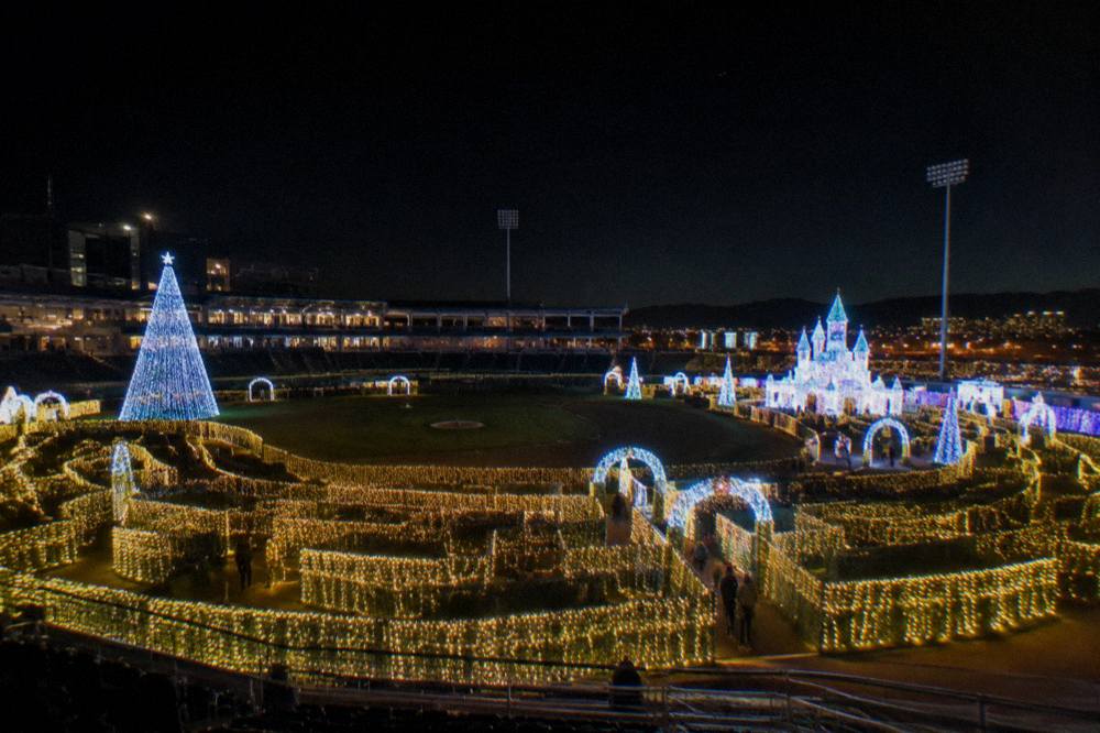 A wide view of a Christmas light maze with glowing pathways and illuminated structures at night