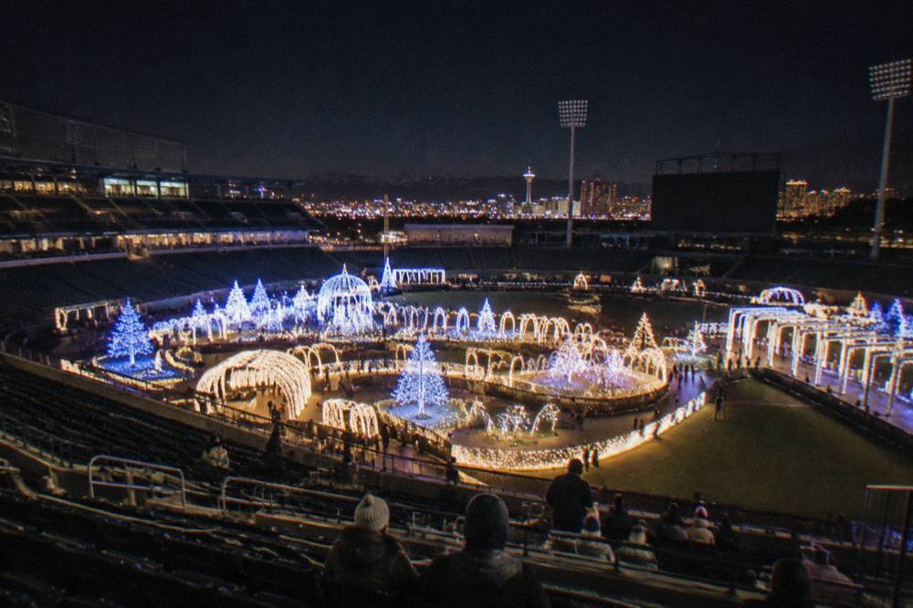 A night view of illuminated holiday light towers and a glowing pathway