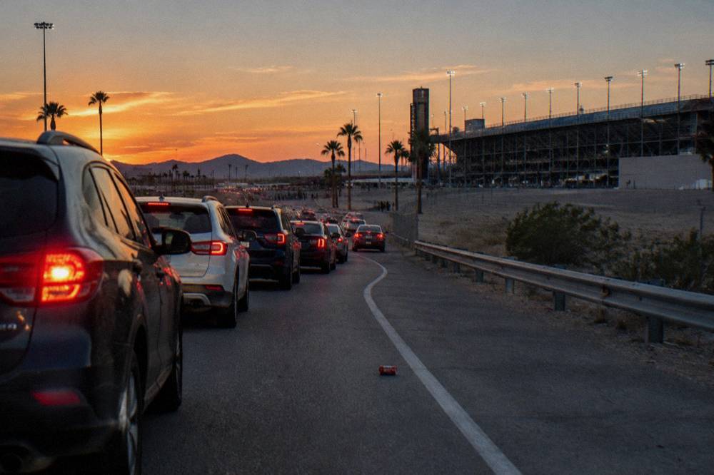 A line of cars waiting at a light show entrance gate at dusk