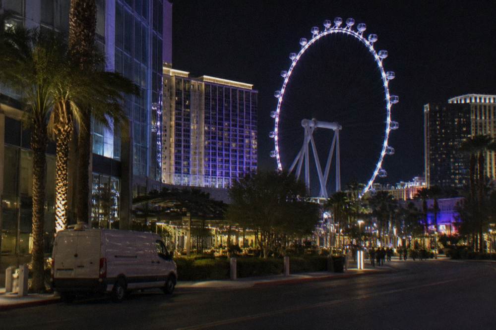 A tall observation wheel lit at night above a resort corridor