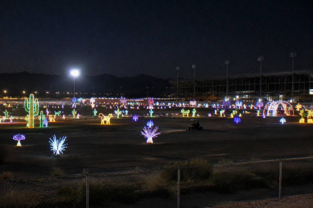 A wide view of a speedway grounds covered in glowing light displays at night