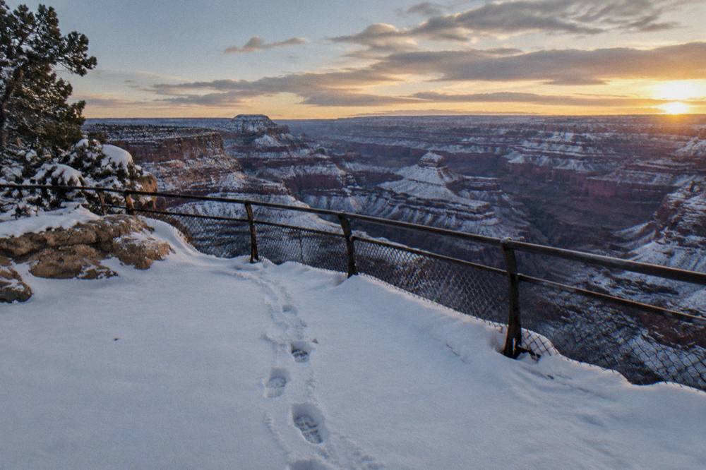 Empty overlook railing above a vast snowy canyon landscape