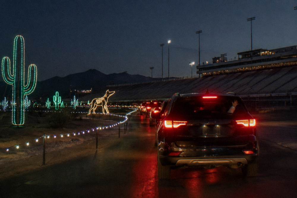 A car waiting in line at a drive-through holiday light display after dark