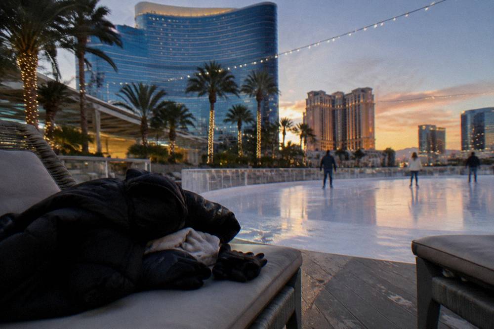 Folded jackets and gloves stacked on a bench beside an outdoor rink