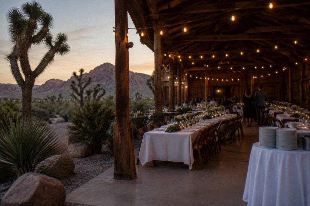 A rustic barn venue with string lights and long dinner tables set for an evening show