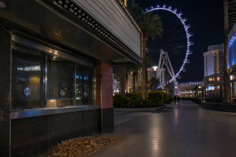 A closed theater box office window at night on a quiet promenade