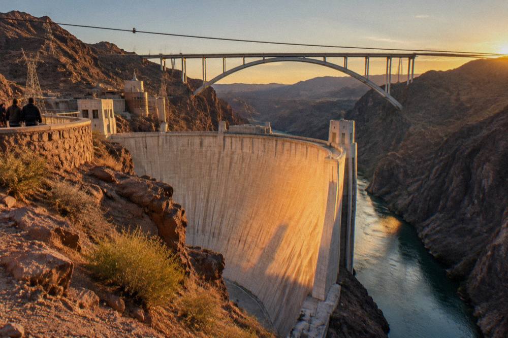 Concrete arch dam face rising from a rocky river gorge in winter light