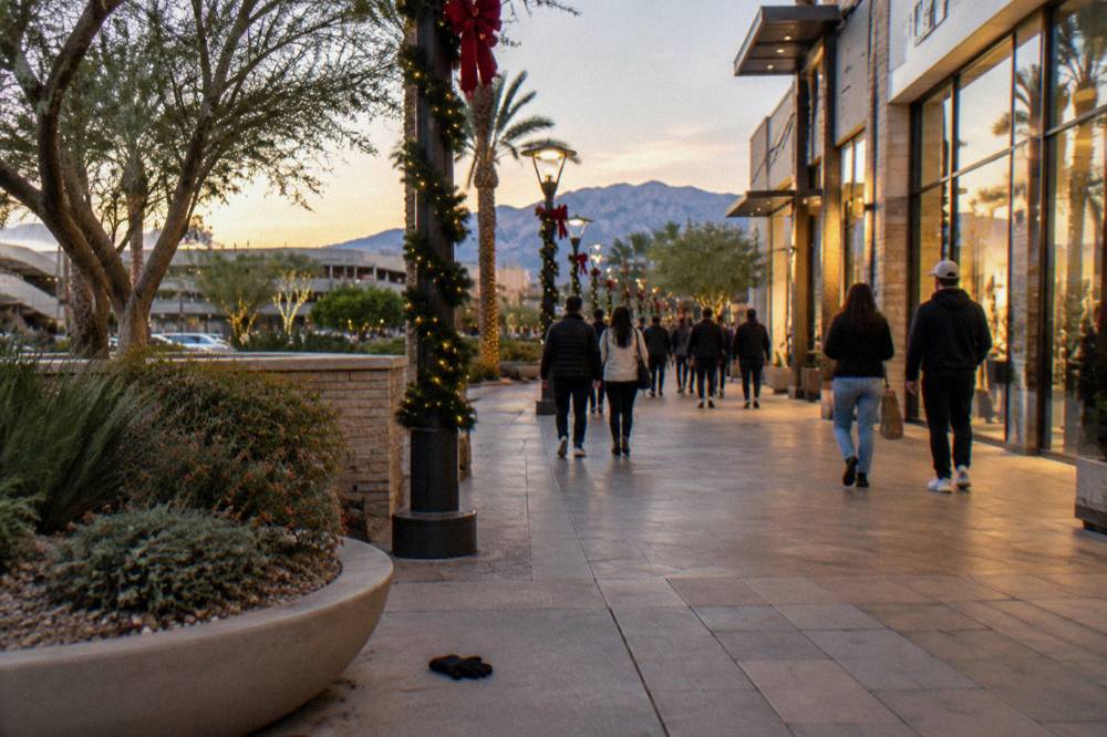 A busy Las Vegas sidewalk at night with illuminated resort signage and holiday crowds