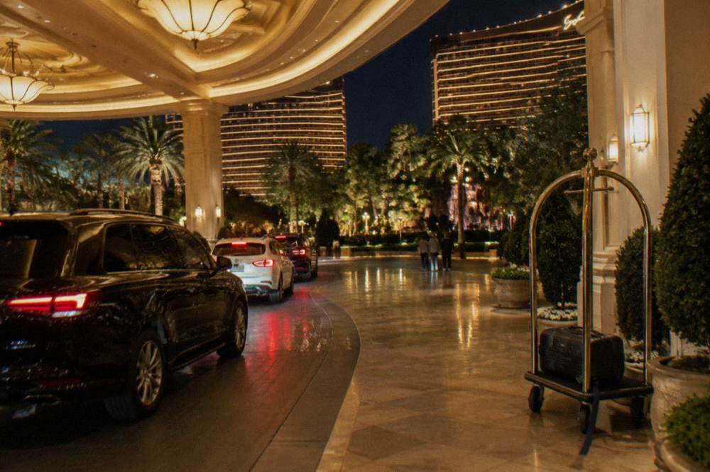 A Las Vegas resort entrance at night with cars in a covered porte-cochere and glowing lobby lights