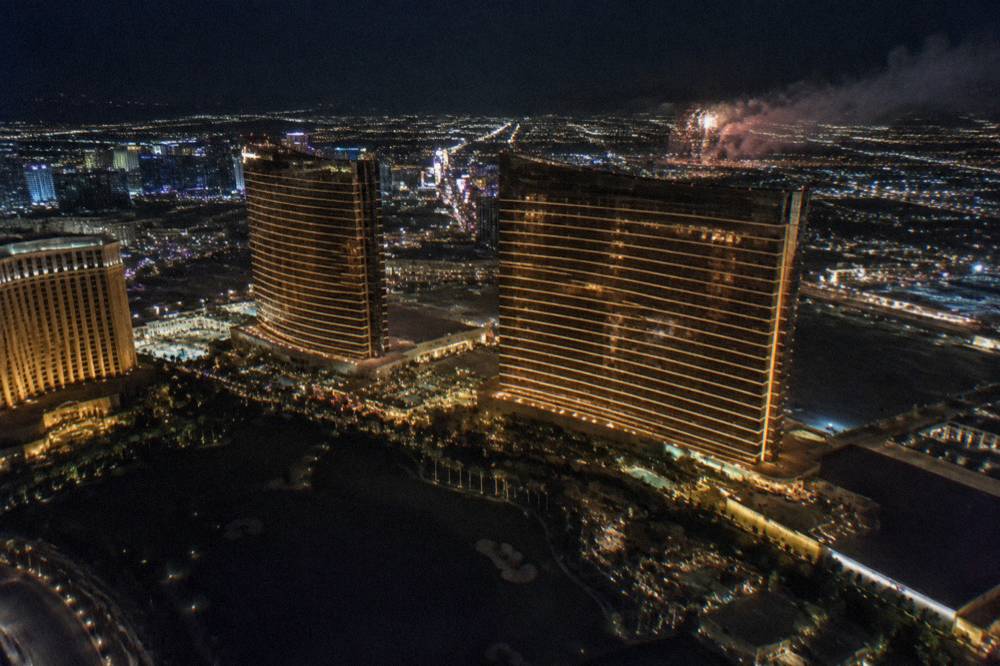 Nighttime aerial view of illuminated hotel towers and boulevard lights below