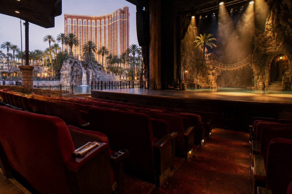 A theater stage lit with spotlights above rows of empty red seats