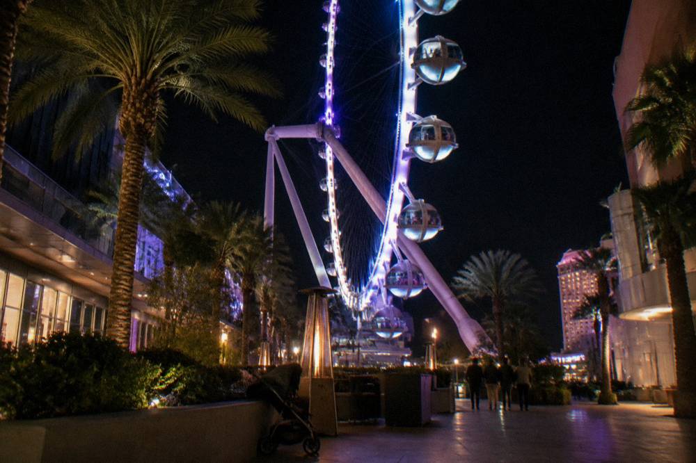 Illuminated observation wheel cabins rising above the Strip at night