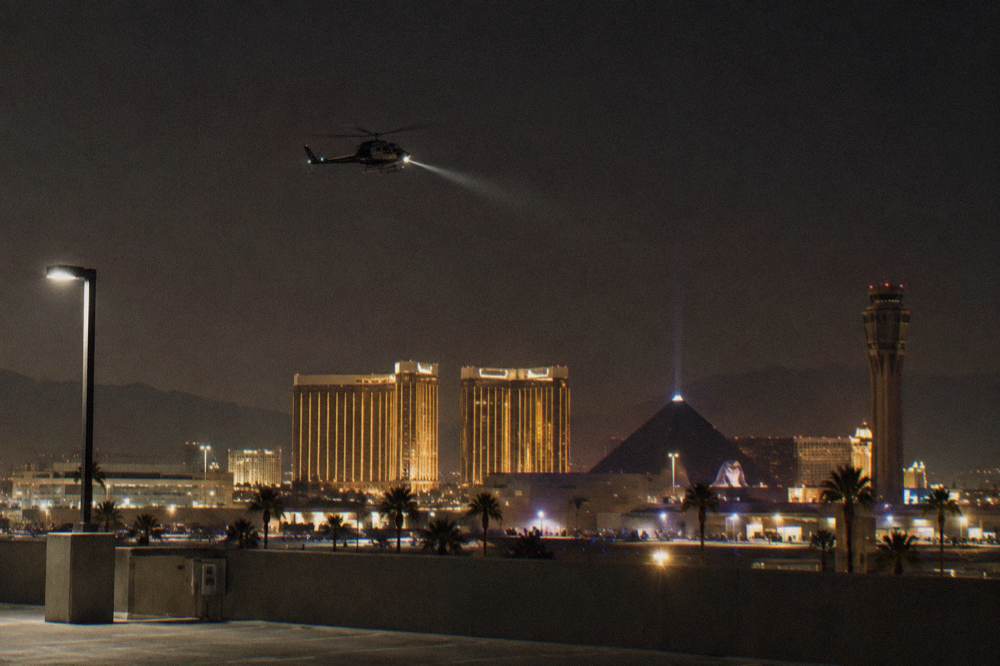 A helicopter flying over brightly lit resort towers on the Strip at night