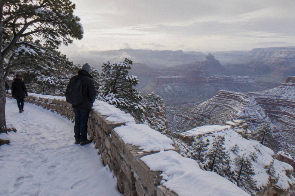 A red rock canyon landscape with light snow dusting the ridges under a winter sky