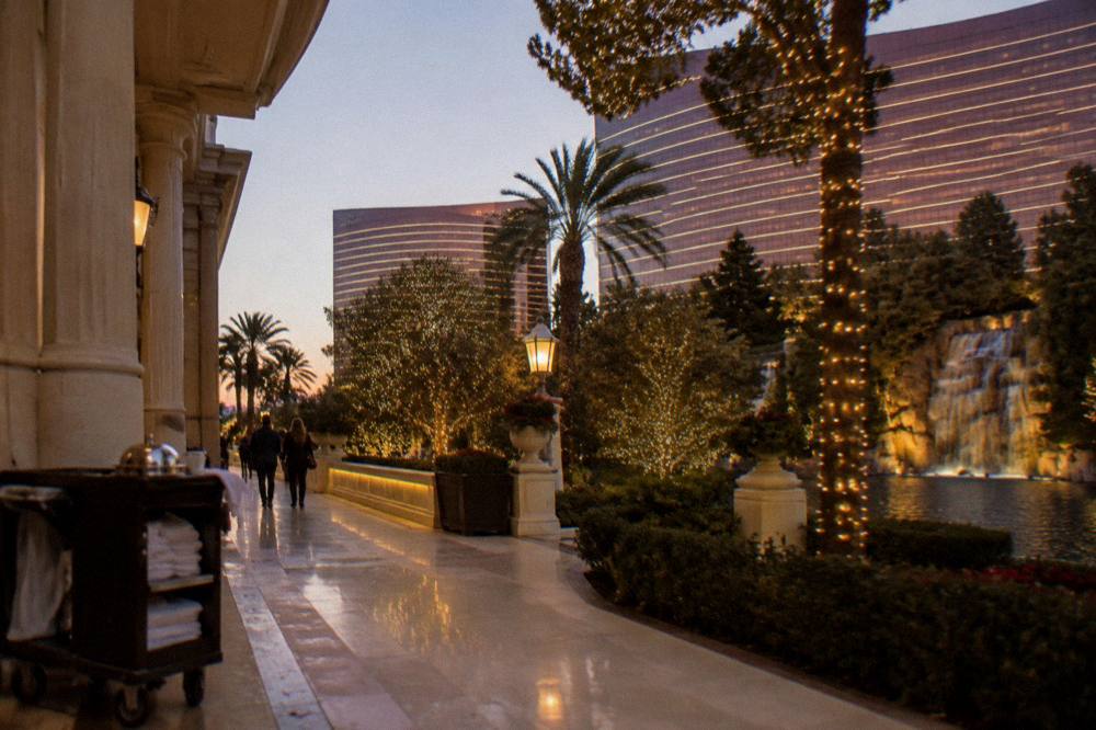 A city street lined with illuminated holiday trees and glowing resort facades in the early evening